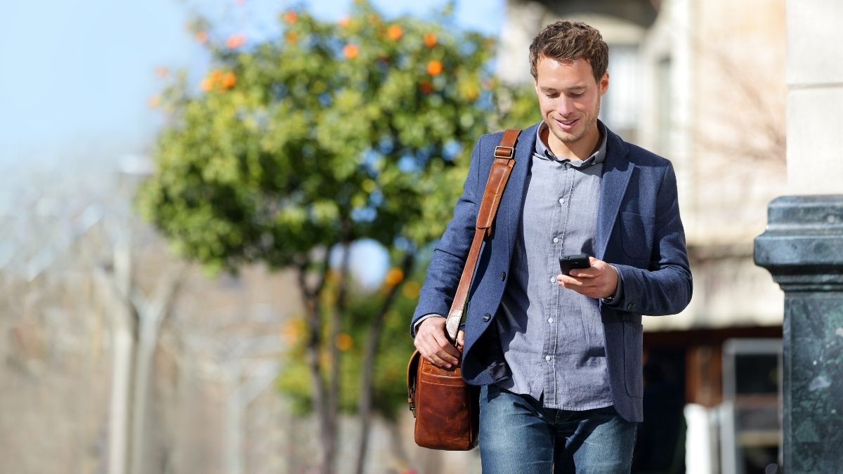Man walking outside holding mobile phone