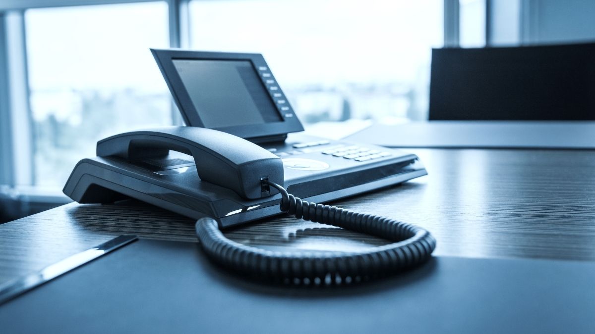 VoIP phone handset on desk in front of window
